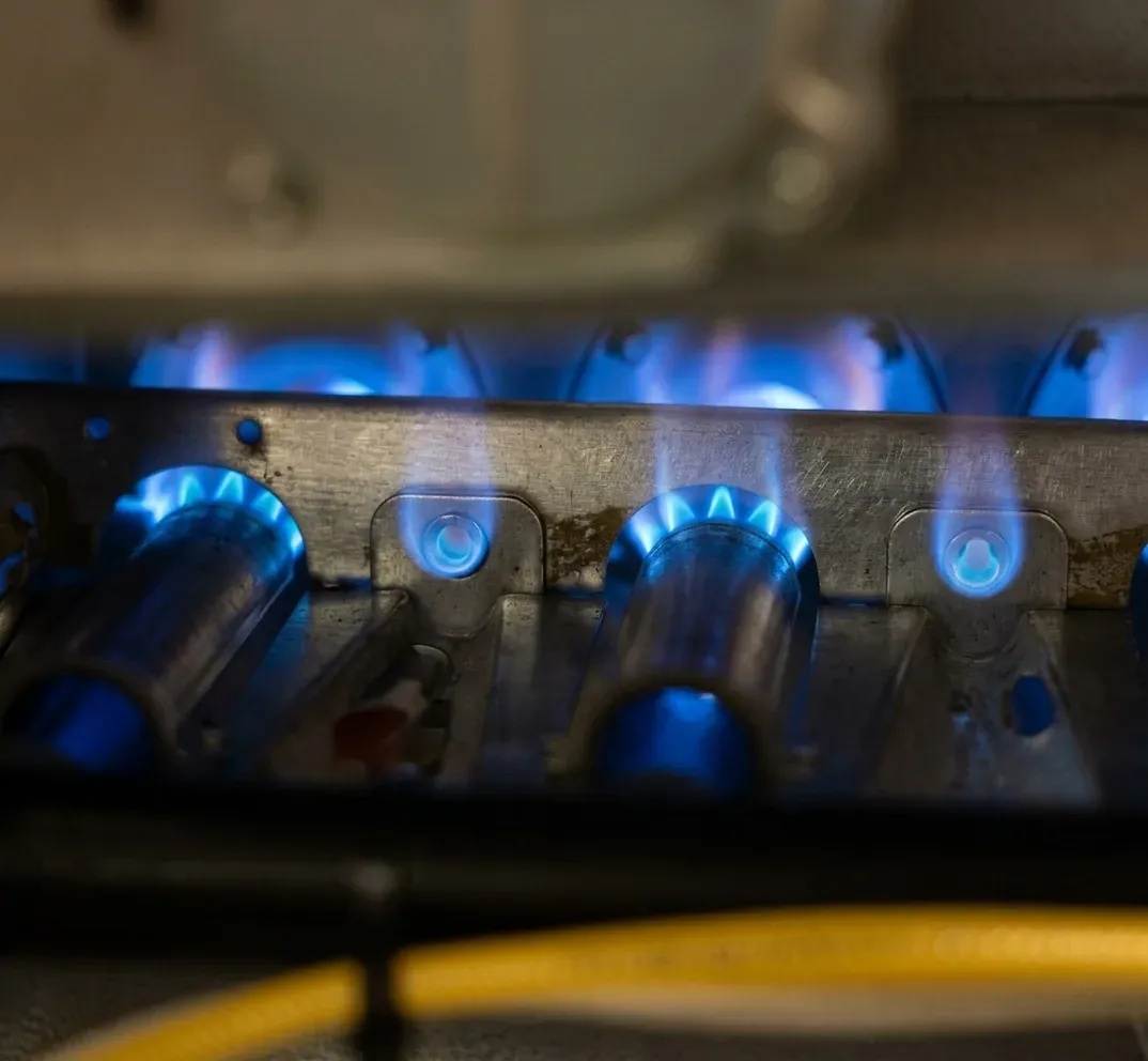 Close-up of gas furnace burners with steady blue flames